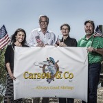The team at Carson and Company holding up a banner with their logo.
