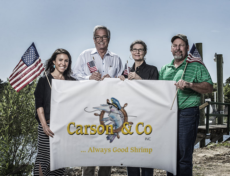 The team at Carson and Company holding up a banner with their logo.