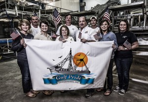 The team at Gulf Pride Enterprises holding up a banner with their company logo.