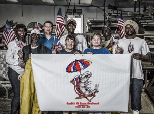 The team at Smith & Sons Seafood holding up a flag with their company logo.