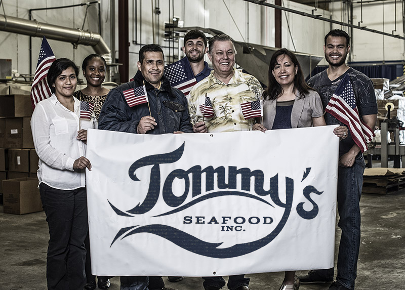 The team of Tommy's Seafood holding up a banner with their company logo.