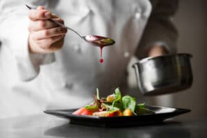 A chef pouring sauce over a meal.
