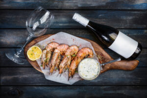 A plate of wild-caught American shrimp paired with a glass and bottle of wine.