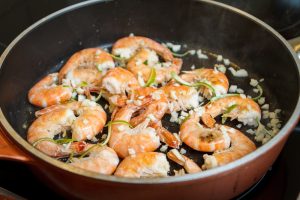 Shrimp cooking in a pan with vegetables.