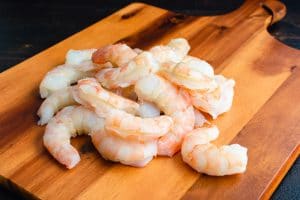 A stack of shrimp on a wooden plate.