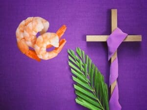 A picture of shrimp alongside a cross wrapped in purple cloth and palm leaves for Lent.