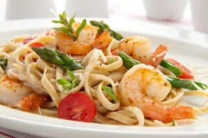A plate of shrimp pasta with vegetables.