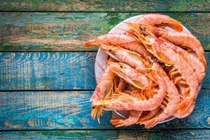 A plate of shrimp on a blue wood background.