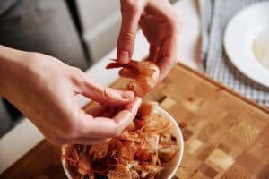 A close-up of a woman's hands peeling shrimp.