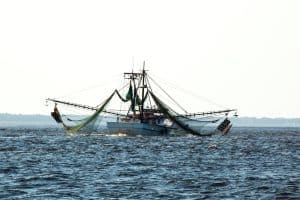 A shrimp boat on the water with its nets cast out.