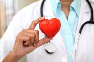 A doctor holding a small heart symbol between their fingers.